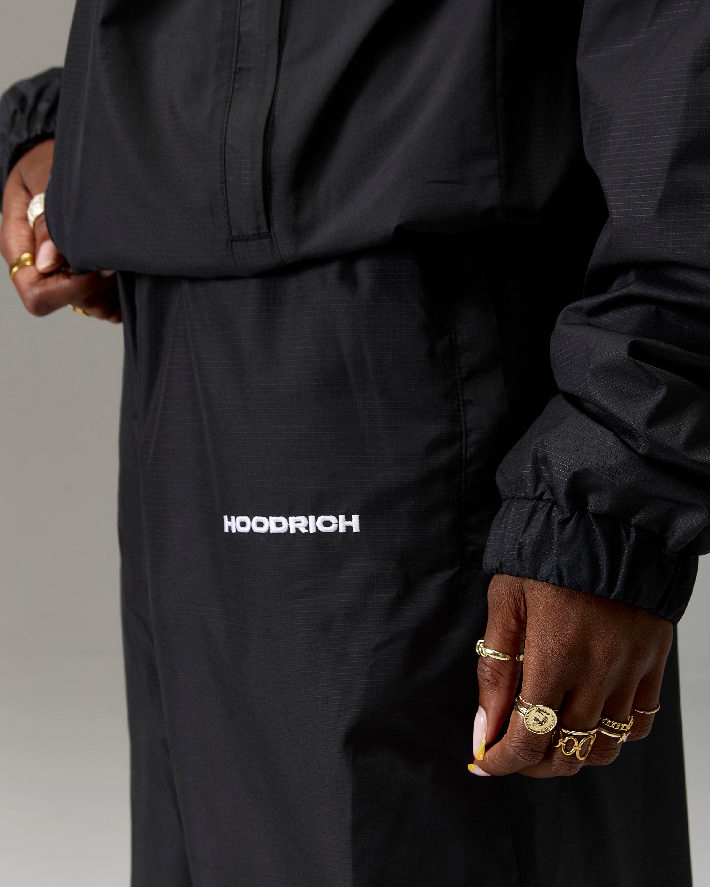 Displays a model wearing the Black 'Hoodrich' branded women's The Winner's Circle Ripstop Woven Full Tracksuit