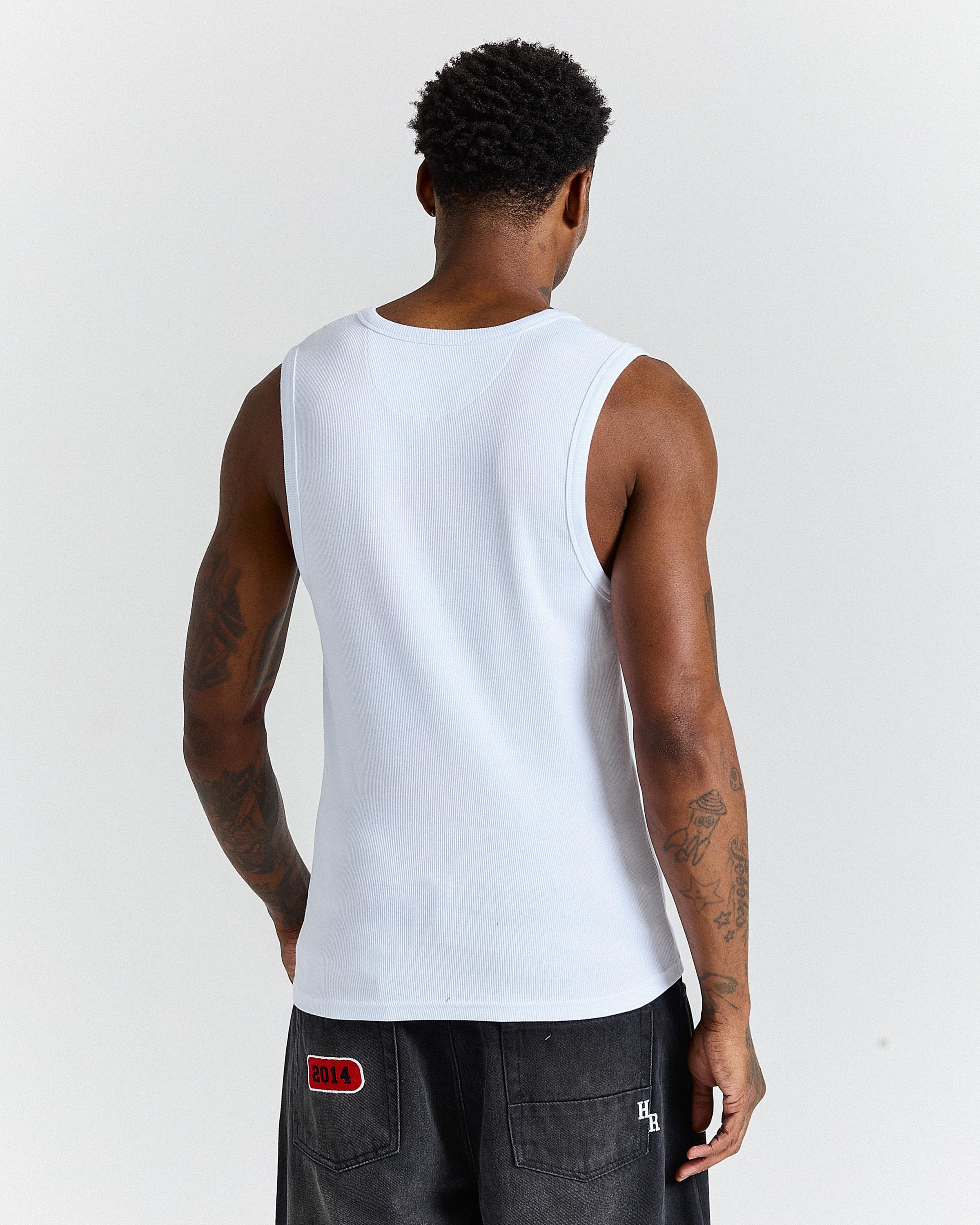 Person wearing a white tank top against a plain background