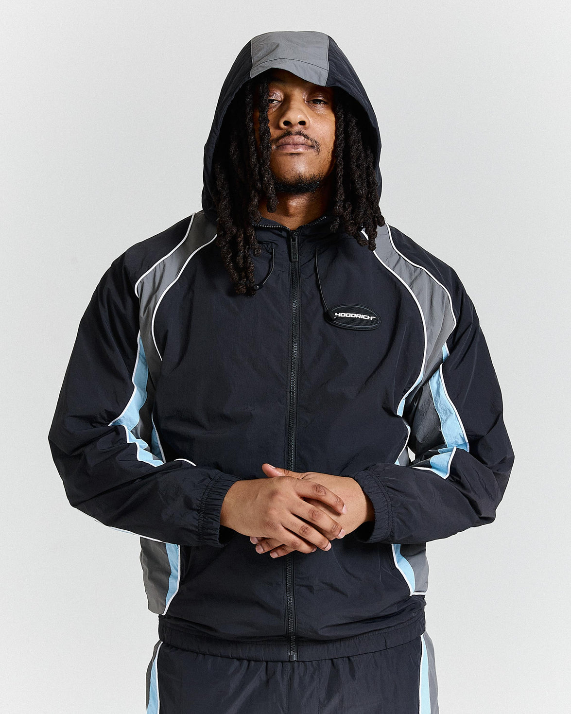 Person wearing a black and gray jacket with a hood on a light gray background
