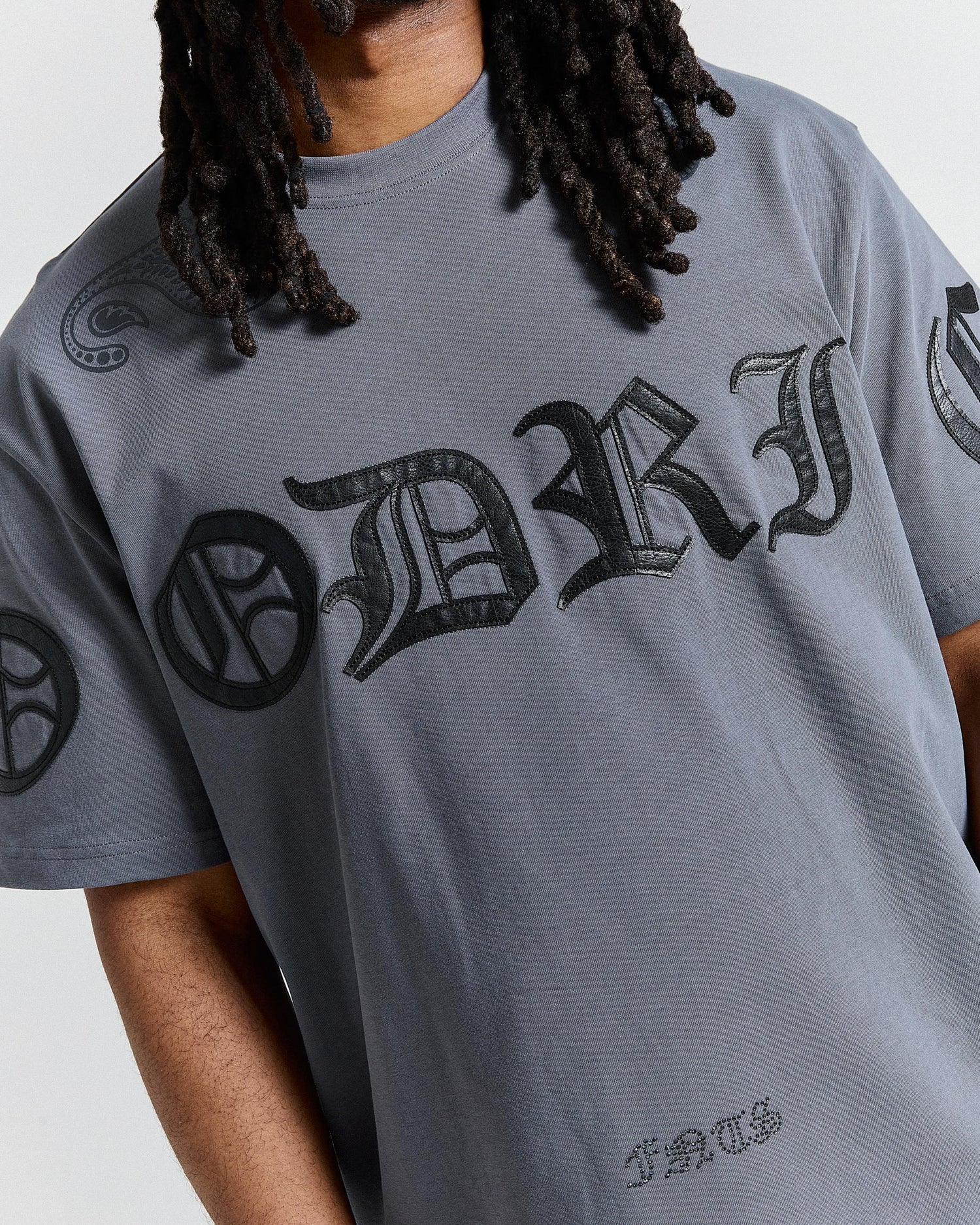 Person wearing a gray t-shirt with black text and graphics on a plain background