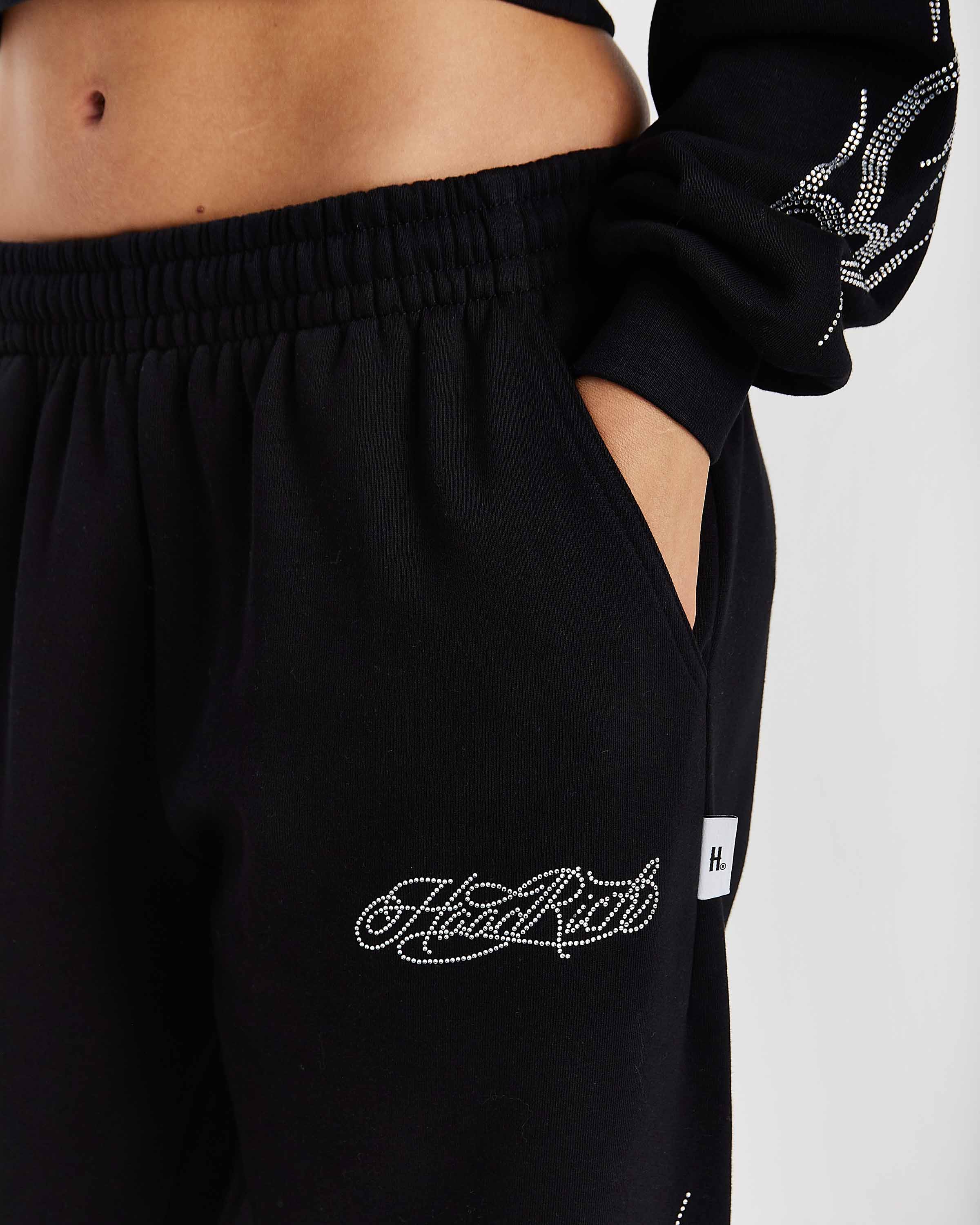 Black sweatpants with rhinestone embellishments on a plain background