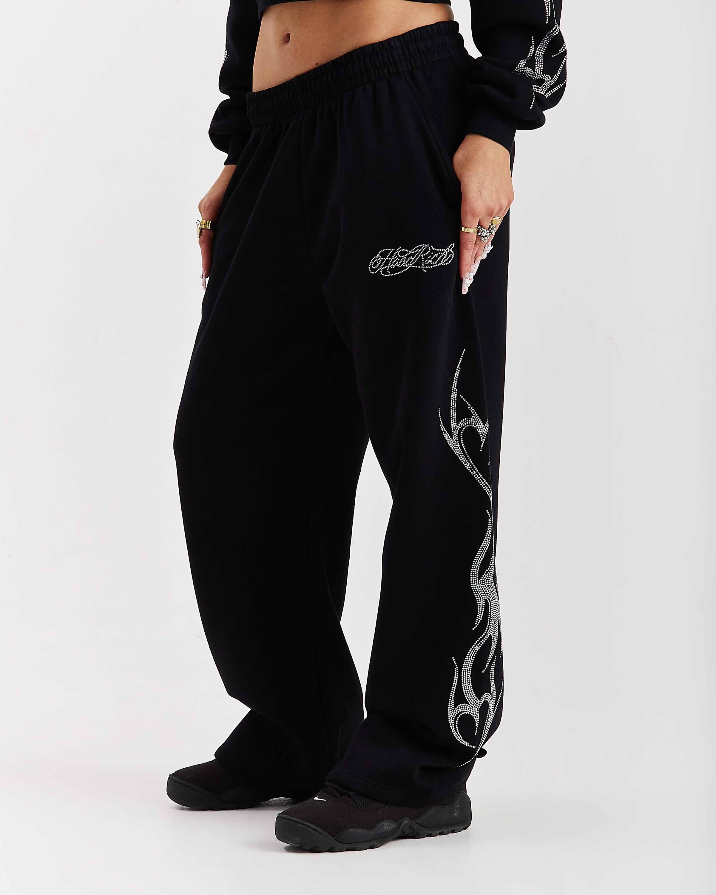 Black sweatpants with tribal designs and brand logo on a white background