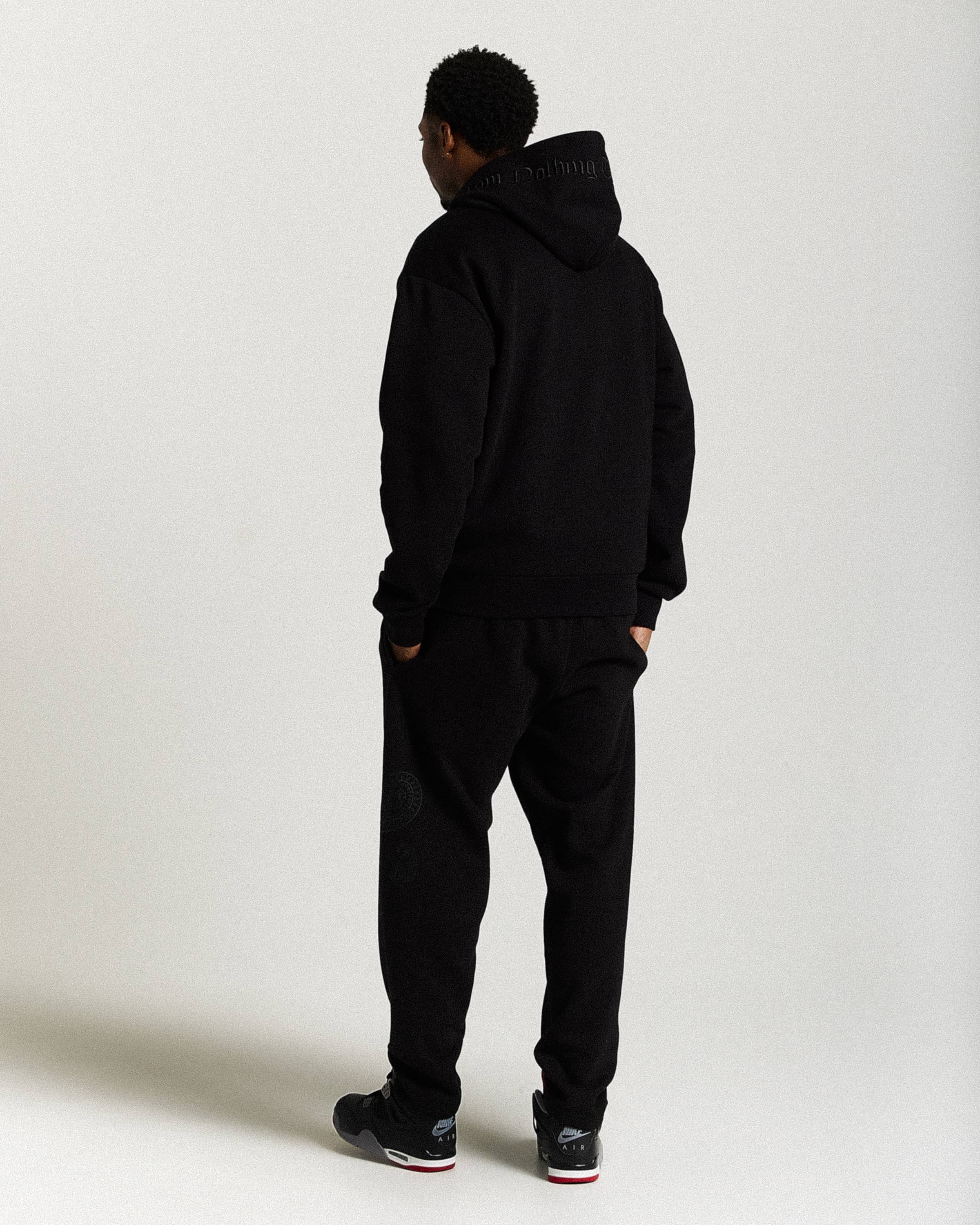 Displays a model wearing the Black 'Hoodrich' branded men's Inkline Full Tracksuit