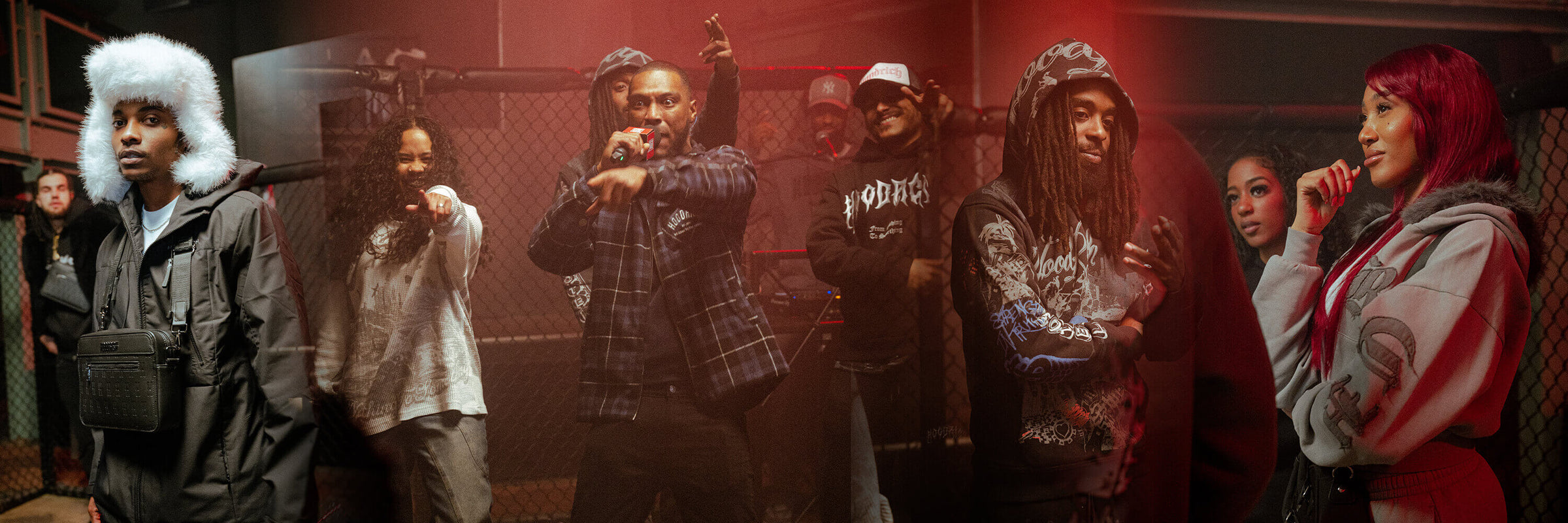 A group of young men standing together in a dimly lit indoor setting with dramatic red lighting. All are wearing hoodrich streetwear, including hoodies, plaid shirts, and caps.